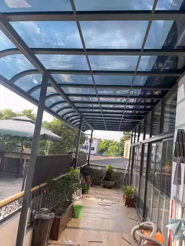 Modern glass awning covering a sunny outdoor patio with plants, by Kings Awning