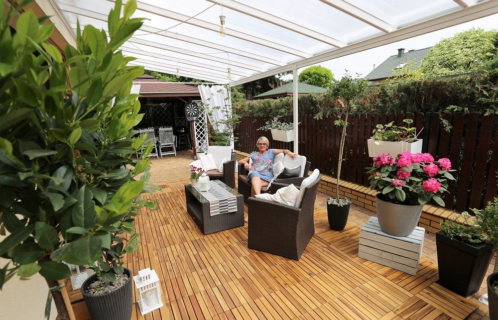 Modern patio with aluminium awning, outdoor seating, decking, and potted plants